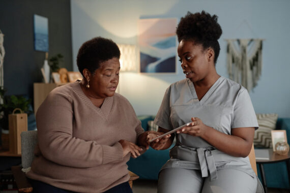 Caregiver showing senior woman how to use digital care app